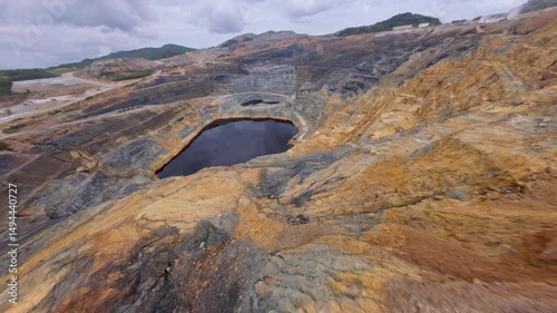FPV drone flight over open-pit gold and silver mine in Cotui, Dominican Republic. Cloudy day in rocky landscape. photo