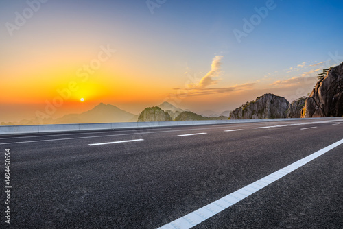 Asphalt highway road and beautiful mountain landscape at sunset