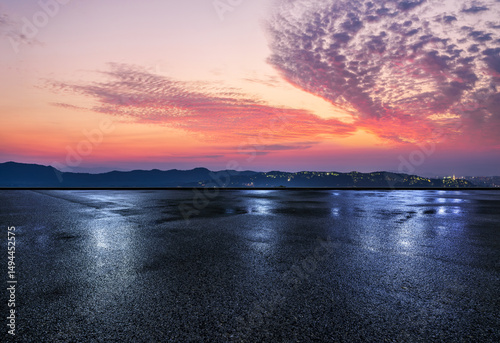 Wet asphalt road and mountain with dramatic sky clouds at dusk