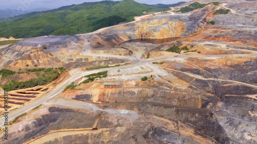 Aerial approaching shot of gold silver mine during sunny day in Dominican Republic. Wide shot. Street and roads with green mountains in distance. photo