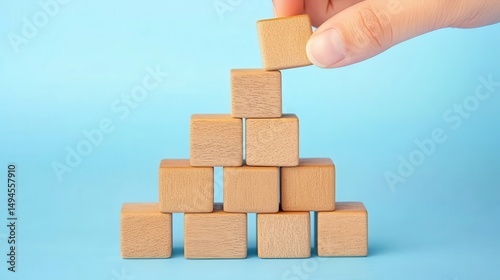 Hand placing wooden block on a pyramid structure