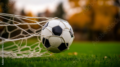 Close-up of a classic black and white soccer ball hitting the back of a white net on a lush green soccer field, dynamic motion, goal moment,