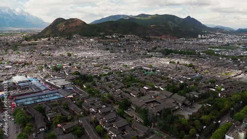 Aerial view of Dayan, the Old Town of Lijiang, in Yunnan, China, traditional Chinese architecture and snow mountains at distance 