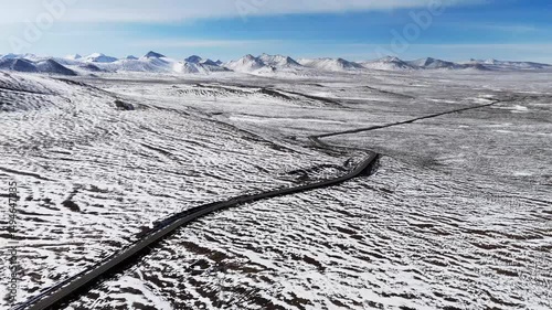 Aerial view of white snow covered mountains landscape with isolated road through  in valley 