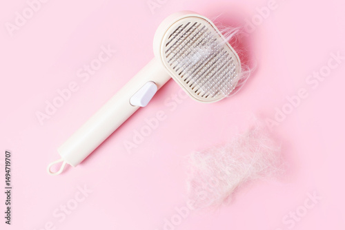 Plastic pet hair brush and heart shaped fur on pink background close-up top view.