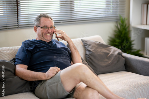 An elderly man is talking on the phone with a happy expression.