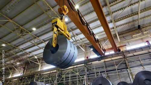 a crane lifts a roll of tinplate
