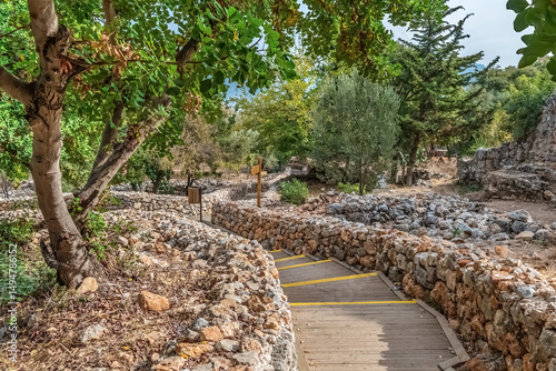 A scenic pathway in Alanya Castle, Turkey, lined with rustic stone walls and surrounded by lush greenery. The pathway leads through the historical ruins, creating a peaceful atmosphere for exploration