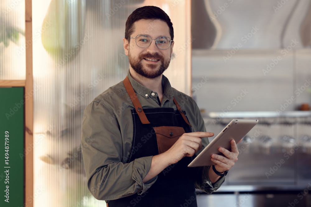 Fototapeta premium Portrait of smiling business owner with tablet in his cafe