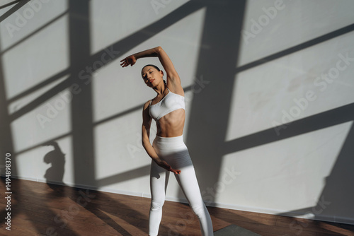 Warm up exercise. Beautiful young woman with slim body type is indoors