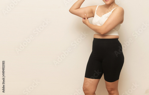 Schilderij op canvas Midsection of a woman in workout clothes pinching underarm fat, highlighting loo