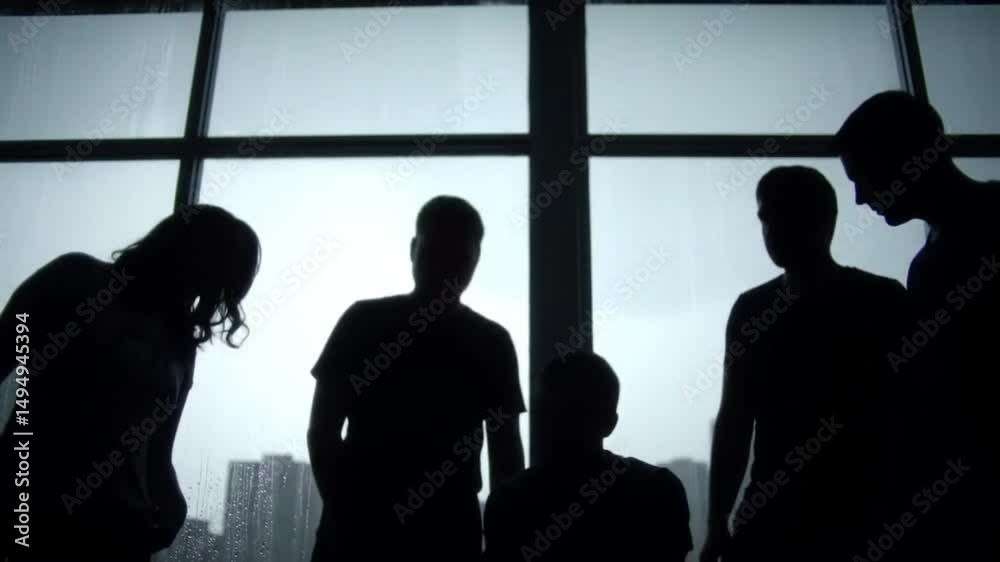 Group of people silhouetted against large window in urban setting during a thunderstorm Group of people silhouetted against large window in urban setting during a thunderstorm