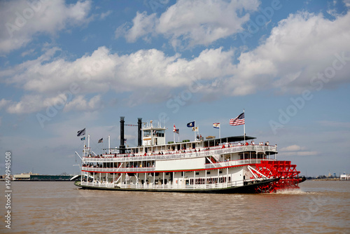 Paddle steamboat cruising on a river under a partly cloudy sky. Road Trip USA