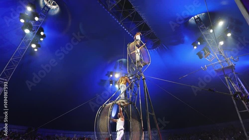 Brave male acrobats in the rotating wheel of death perform under the dome of the circus.