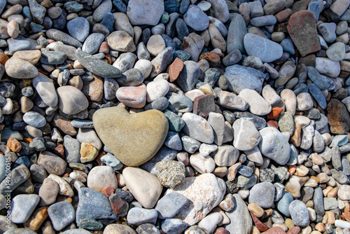 Fototapeta Naklejka Na Ścianę i Meble -  a beautiful, large, weighted stone as a heart shape between the many colorful pebbles on the beach in Kemer Turkey