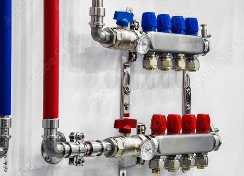 Industrial plumbing system with colored valves and pressure gauge in a factory setting