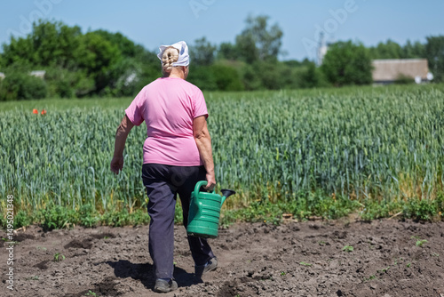 Concept farm, agrocomplex. A female farmer waters young shoots of agricultural crops by hand on her farm