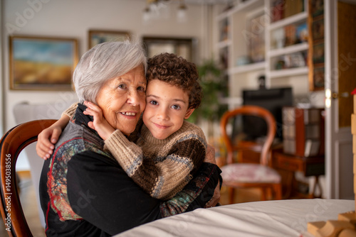 Grandchild hugging grandmother at home playing with wooden blocks