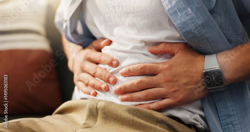 Stomachache, hands and person in home, pain and man with food poisoning in living room or indigestion. Abdominal, cramps and discomfort on couch, gas and bloating in lounge, diarrhea or constipation