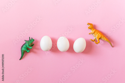 Easter egg hunt holiday composition, white eggs with dinosaur on light pastel pink backgroind. Seasonal spring kids game concept. Flat lay, minimal, trendy, top view, place for text, banner
