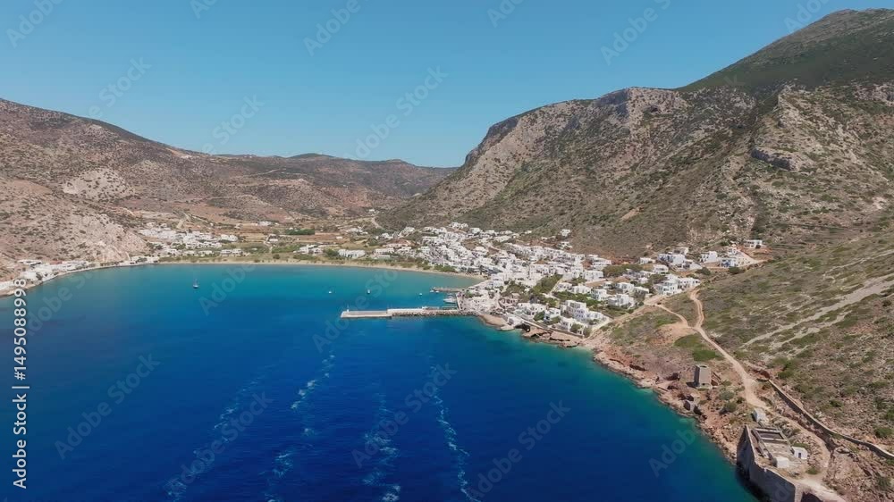 Drone pullout from Sifnos port over Kamares Bay showing water, boats, and Cycladic landscape