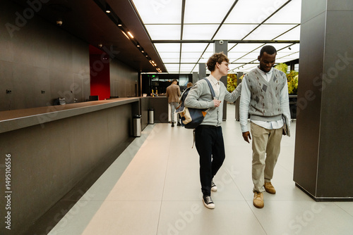 Fotografía Male intern walks and pats on the back a male employee who walks next to him and