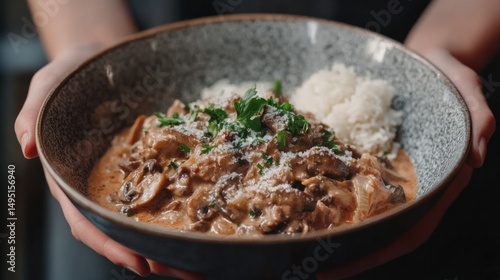 Warm hearty bowl of creamy beef stew garnished with fresh herbs, served with fluffy white rice in a rustic ceramic bowl, perfect for comforting meals photo