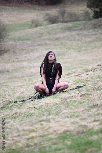 Hexe im schwarzen Kleid vor dem Wald 