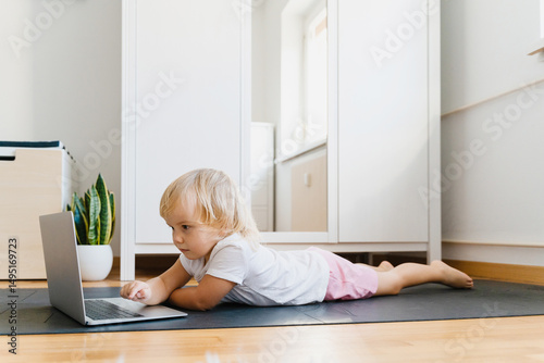 Little children using laptop while lying on floor.
