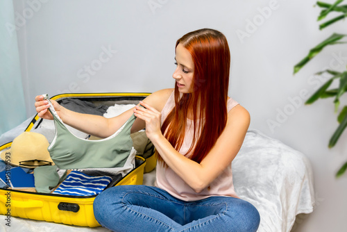 Happy woman girl getting ready for travel,packing clothes in suitcase.preparing luggage for road trip,vacation.traveling, adventure.planning summer holiday.
