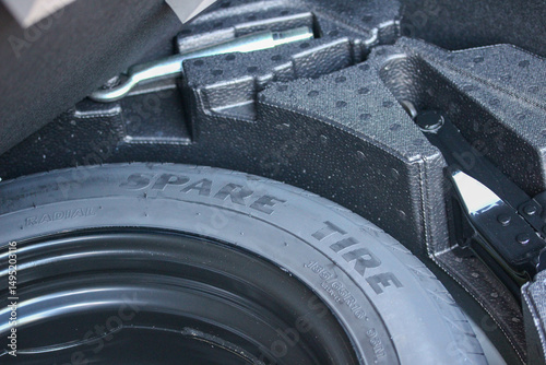 Close up view of a new vehicle spare tire, jack and wheel spanner