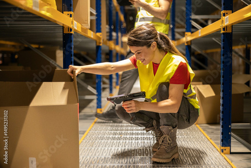 A woman in a yellow vest scans items in a warehouse, highlighting the importance of organization and safety in logistics operations.