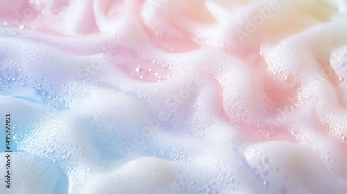 Photograph of textured foam, blending pale blue and pink hues with droplet details.