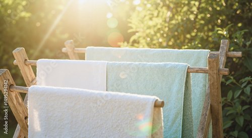 Towels drying on wooden rack in sunny garden with lens flare

