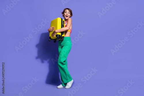 Photo of positive pretty girl wear trendy clothes hold valise summer vacation tour abroad empty space isolated on purple color background