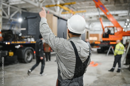 Construction worker directing operations in prefabricated building factory