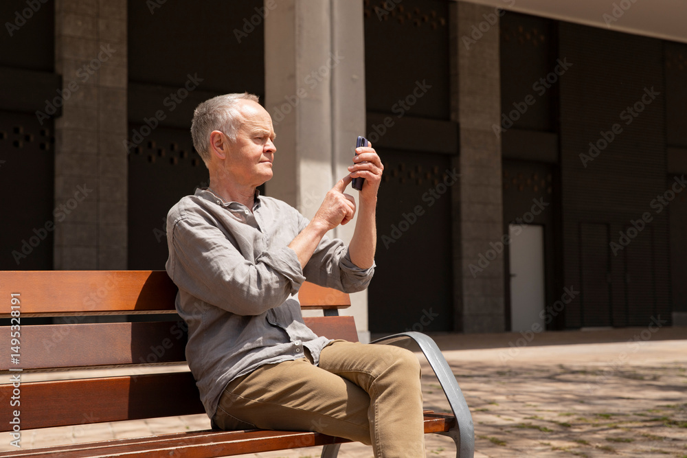 Fototapeta premium Outdoor portrait of man on smartphone. Man over 60 using phone