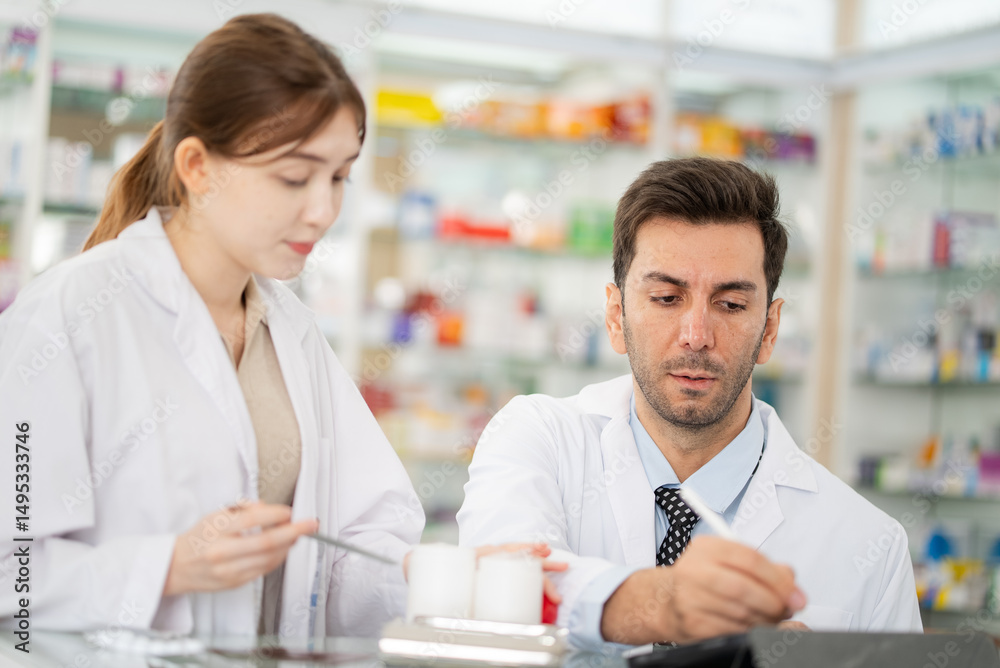 Two pharmacists counting drug pills arranging assortment working in drug shelves counter Two pharmacists counting drug pills arranging assortment working in drug shelves counter