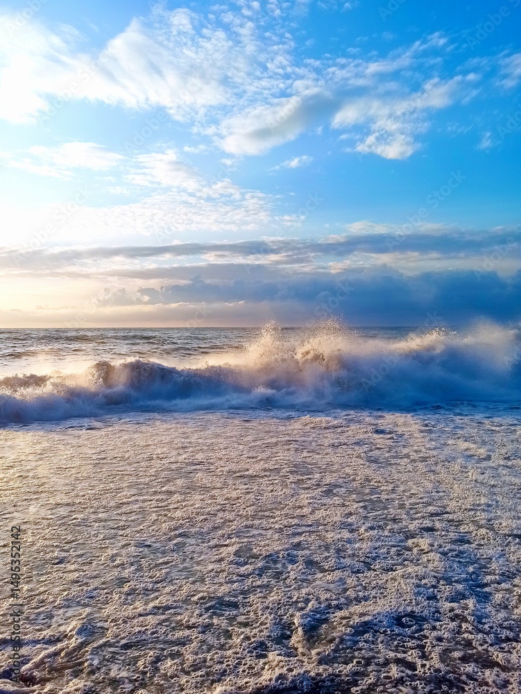 Obraz premium Vertical photo of large waves on the Black Sea at sunset, Batumi, Georgia, dramatic seascape, ocean energy, coastal view, evening light, nature power, sea foam, travel destination, golden hour. 