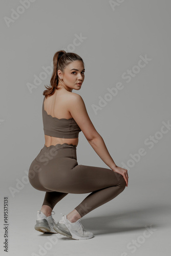 Wallpaper Mural Fitness enthusiast performing a squat in stylish activewear during a studio session Torontodigital.ca