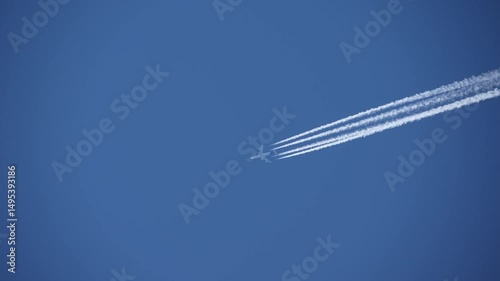 Looking up four engine passenger airplane with vapor trails in the sky on a sunny spring day. Slow motion movie shot May 11th, 2025, Zurich Kloten, Switzerland.