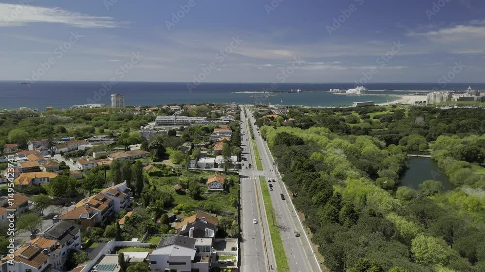 Drone flies northwest along Avenida da Boavista next to Parque da Cidade do Porto on sunny day in Porto, Portugal