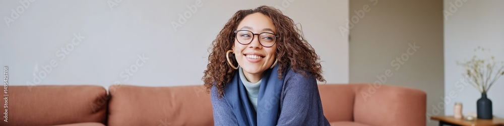 Obraz premium Young african female smiling on sofa with glasses in cozy living room setting