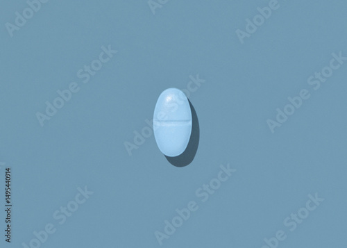 Oval blue Medical pill on blue top view, hard shadows. Preventive medicine and healthcare