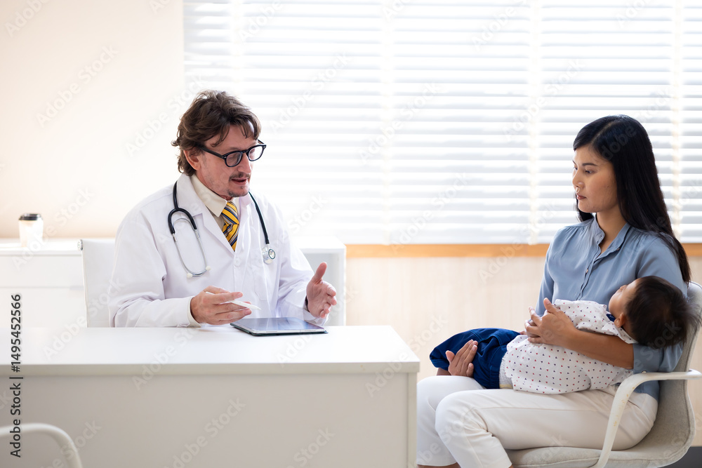 Fototapeta premium pediatrician : Hispanic or caucasian male Doctor working with little asian boy patient and family at hospital and wellness center.