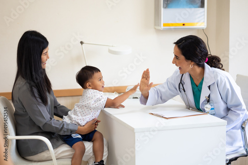pediatrician : Hispanic Brazilian woman Doctor working with little asian boy patient and family at hospital and wellness center.