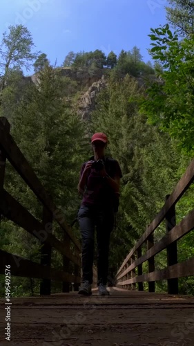 woman photographing forest landscape on wooden bridge in Bionaz alps