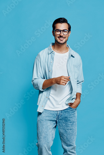 Smiling happy cheerful young man wearing a light blue shirt smiles at the camera while holding a pen, isolated on a solid light blue background. Lifestyle concept.