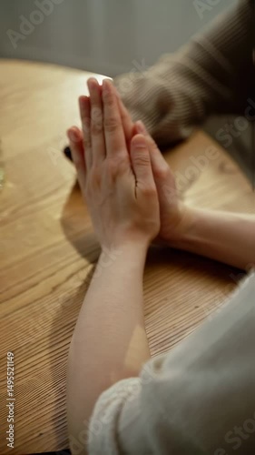 Wallpaper Mural Hands in prayer position at a wooden table during a quiet moment of reflection Torontodigital.ca