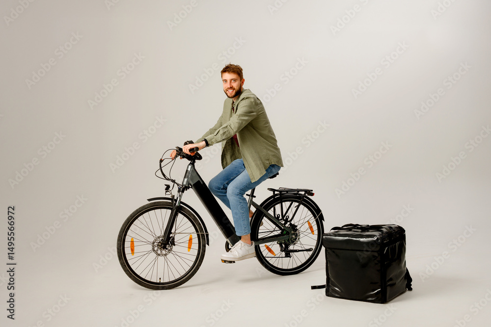 Naklejka premium Delivery cyclist posing with bike and insulated bag in studio setting for promotional purposes